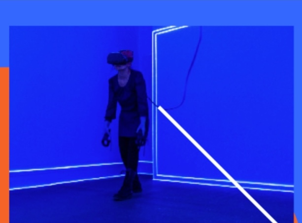 RDS Visual Art Awards | Friday 21 November 2025 – Sunday 25 January 2026 | Royal Hibernian Academy | Image: figure in a dark outfit – top, skirt, tights – in a very blue space, wearing VR headgear and holding VR holdy things; we see neon lines of various sorts 