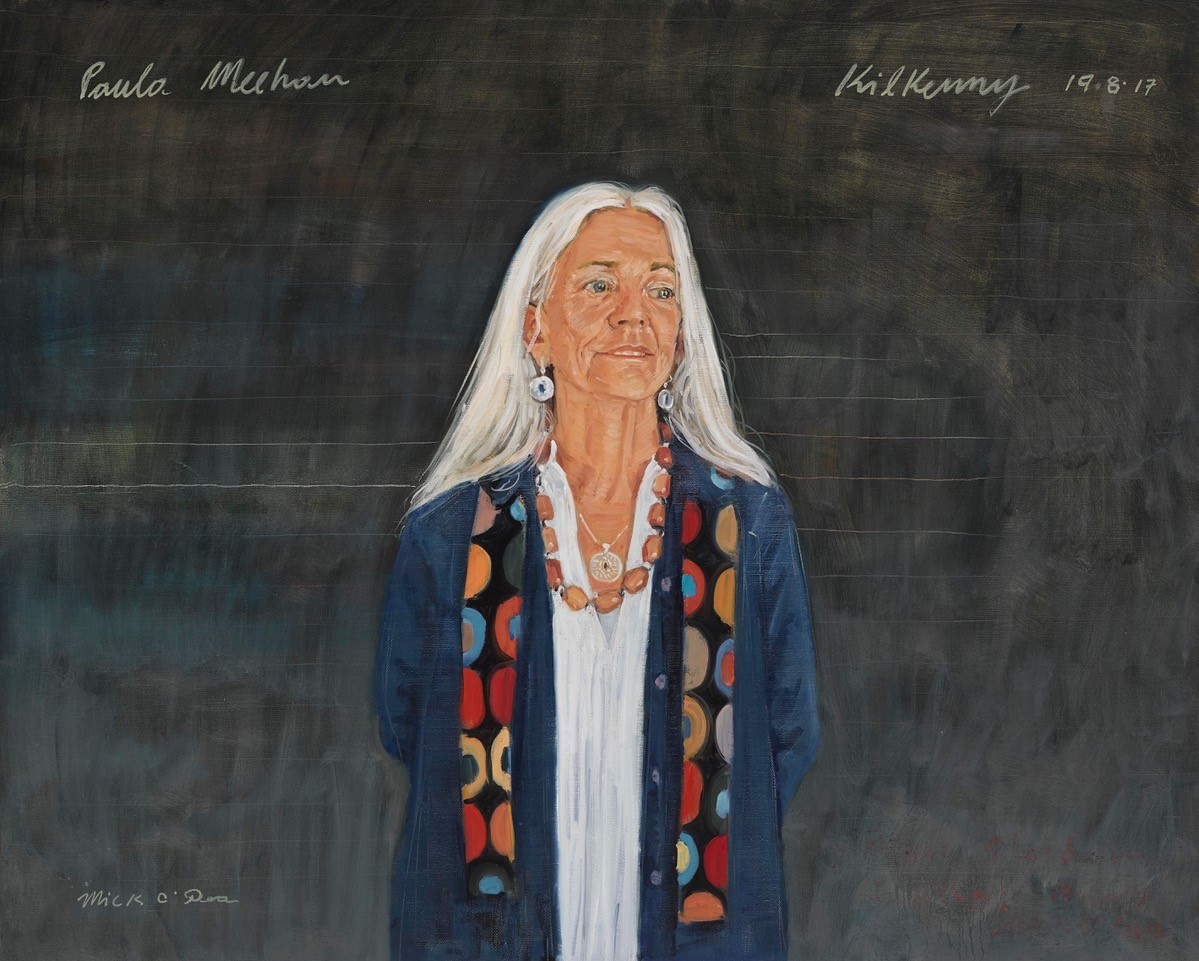 Mick O'Dea | New Acquisitions | Tuesday 1 November 2022  – Sunday 9 July 2023 | Hugh Lane Gallery | Image: painted portrait of poet and playwright Paula Meehan, wearing open blue jacket, colourful scarf, chunky necklace, circular earrings, looking somewhat to her left, all against a background suggestive of a large school blackboard  