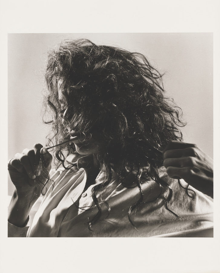 Peter Hujar: Lynn Davis (Pulling Hair), 1981 Gelatin silver print | Influence and Identity: Twentieth Century Portrait Photography | Friday 26 May  – Sunday 8 October 2023 | IMMA | Image: Peter Hujar: Lynn Davis (Pulling Hair), 1981 Gelatin silver print  – Lynn Davis head-and-shoulder shot from left, two hands visible pulling strands of unkempt hair 