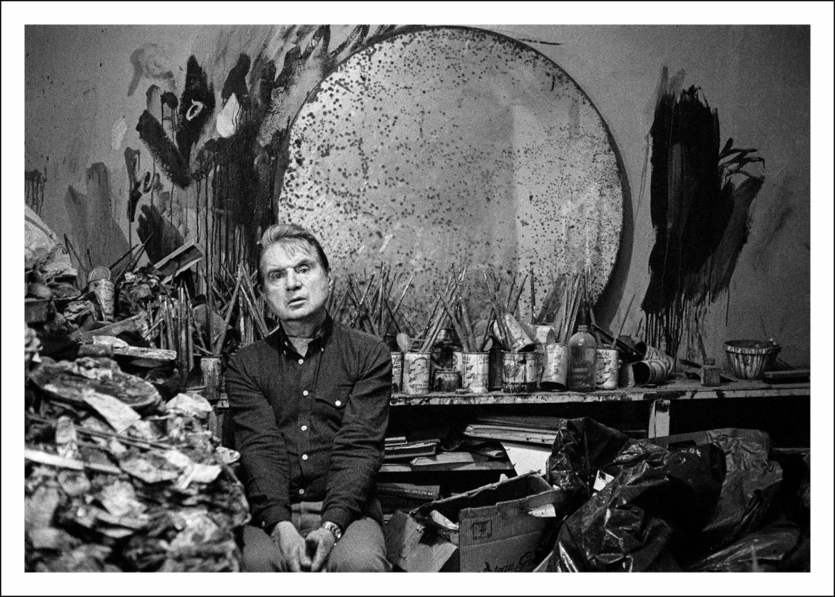 Jane Bown, Francis Bacon, 1980. © Jane Bown Estate | Bown + Bacon | Wednesday 19 July 2023  – Sunday 7 January 2024 | Hugh Lane Gallery | Image: Jane Bown, Francis Bacon, 1980. © Jane Bown Estate – a photo of Bacon in his studio, which has been transplanted to the Hugh Lane; there’s a staggering mess of painting-related materials, much of it tins with paintbrushes sticking out of them; there are also broad brushstrokes on the wall behind, and a very large, round, very tarnished mirror 
