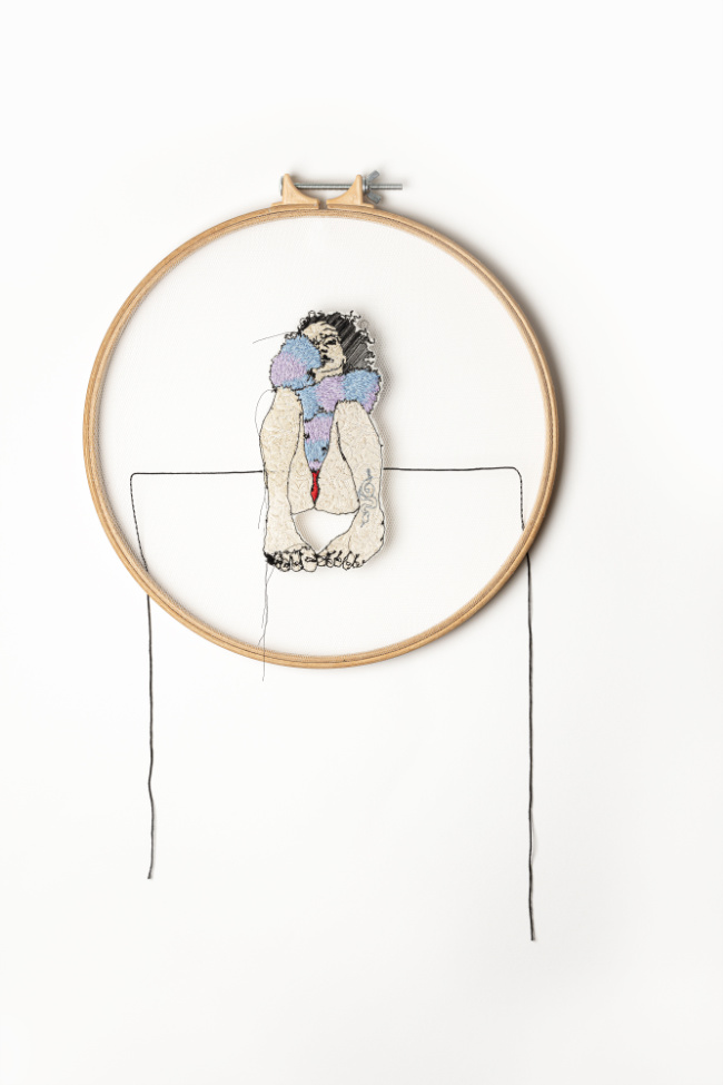 Ciara O'Connor, Self-portrait in Red Knickers, 2022 | Following Threads | Saturday 9 September 2023  – Sunday 28 January 2024 | Crawford Art Gallery | Image: Ciara O'Connor, Self-portrait in Red Knickers, 2022 – photo of a self-portrait by the artist, probably darned and then, or before, cut out along the edges of the portrait; we see the portrait centred in a darning hoop, floating slightly forward of the surface on which the hoop rests, judging by the shadows; there is an incomplete rectangle drawn in pencil (?) on the wall (?), with its top two-thirds of the way down the figure; there are some loose threads hanging from the figure; the figure is viewed as though sitting on a bed with feet drawn up so that the knees are bent; we see red knickers, a chunky pullover (?) and the artist – unkempt dark hair and one eye hidden by the cuff of the sweater – peering at us 