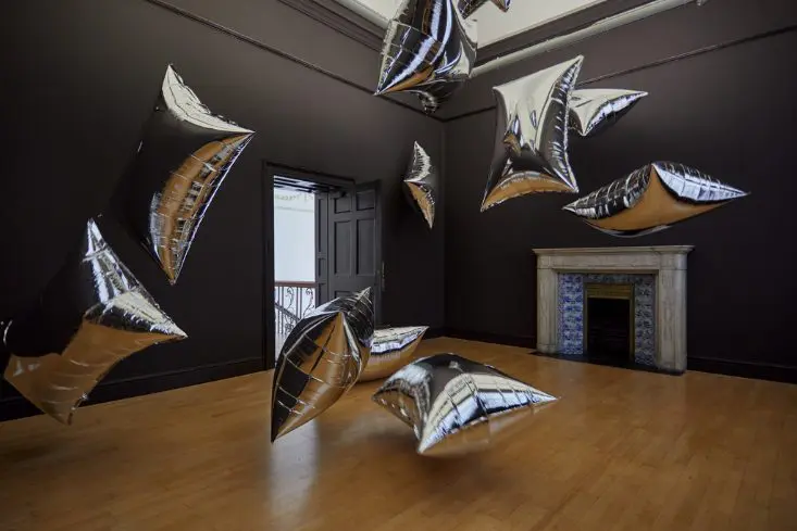 Silver Clouds installation view Hugh Lane Gallery. Photography by Denis Mortell 2023. | Andy Warhol Three Times Out | Friday 6 October 2023  – Sunday 28 January 2024 | Hugh Lane Gallery | Image: Silver Clouds installation view Hugh Lane Gallery. Photography by Denis Mortell 2023. | photo of Warhol’s ’Silver Clouds’, consisting of multiple big-pillow shapes in shiny silver, inflated and suspended randomly in one of the upper rooms of the Hugh Lane; the room itself has black walls, a fireplace on one wall, an open door on another; wooden floor and high ceiling 