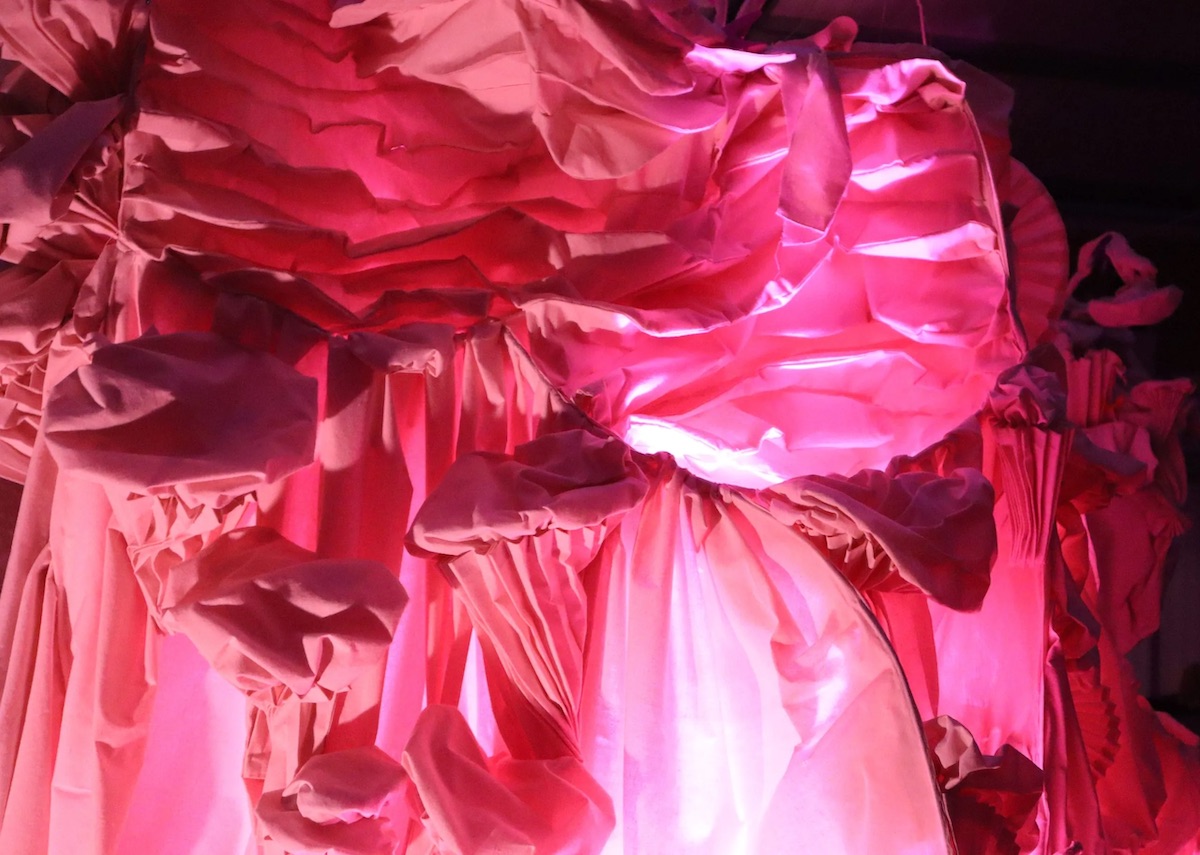 Gillian O’Shea: All Flesh | Gillian O’Shea: All Flesh | Saturday 14 October  – Saturday 25 November 2023 | GOMA Gallery of Modern Art | Image: Gillian O’Shea: All Flesh | probably a photo of white ruched fabric in pink and white light – or possibly pink fabric in white light; the white light comes from below slightly to the right of centre and it catches in the multiple folds; a paler light comes from below left; it doesn’t seem possible to work out what sort of piece of clothing is involved  