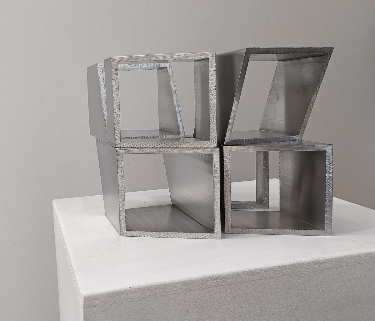 Corban Walker: Under Stand The Space | Thursday 28 September  – Saturday 21 October 2023 | Solomon Fine Art | Image: photo of work by Corban Walker; we see at least six 'tubes' that are square in cross-section and made, by the look of it, out of polished steel; some of the cross-sections are at an angle and we are looking into them more or less straight-on – though more to the side for the farther tubes; the tubes are stacked on each other in pairs; we have no strong indicator of scale, but they may be resting on the base of a plinth 