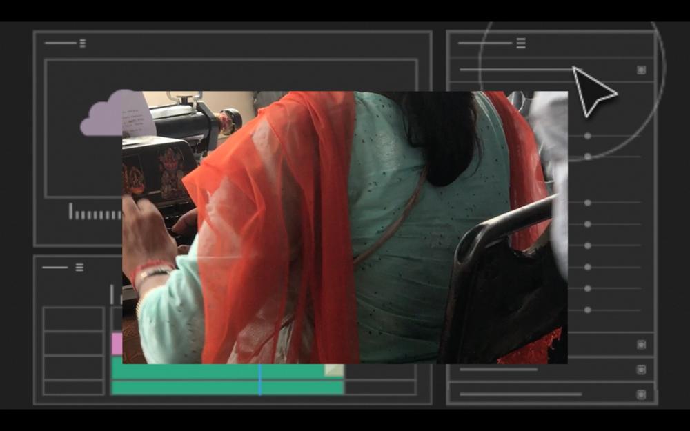 Bindu Mehra, The Inaccessible Narrative (still), 2023. Courtesy of the artist | Bindu Mehra: The Inaccessible Narrative | Saturday 13 January  – Saturday 10 February 2024 | SIRIUS | Image: Bindu Mehra, The Inaccessible Narrative (still), 2023. Courtesy of the artist | photo from behind and to the left of someone working at (probably) a sewing machine; we only see part of the machine, part of the person – from shoulder to waist, hands active at the machine, black hair coming part-way down the back, part of the back of a metal-frame chair; the figure appears to be wearing familiar Indian garb; the photo is centred above a mostly monochrome background that looks like an online template of some sort 