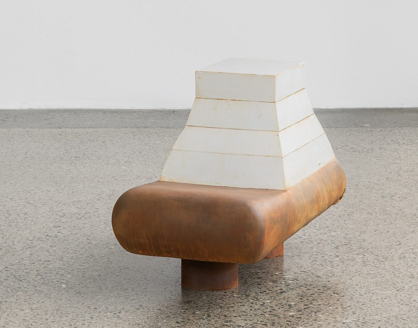 lucent | Saturday 15 June  – Wednesday 31 July 2024 | Wexford Arts Centre | Image: photo of a sculpture; the bottom part of it looks like a stocky, rounded bench, made of wood or copper or rusty steel; on and apparently attached to the bench is a large, mostly white shape that looks like an Aztec temple, though without the detail; it is constructed, apparently, in four bands which are separated by a narrow yellowish band 