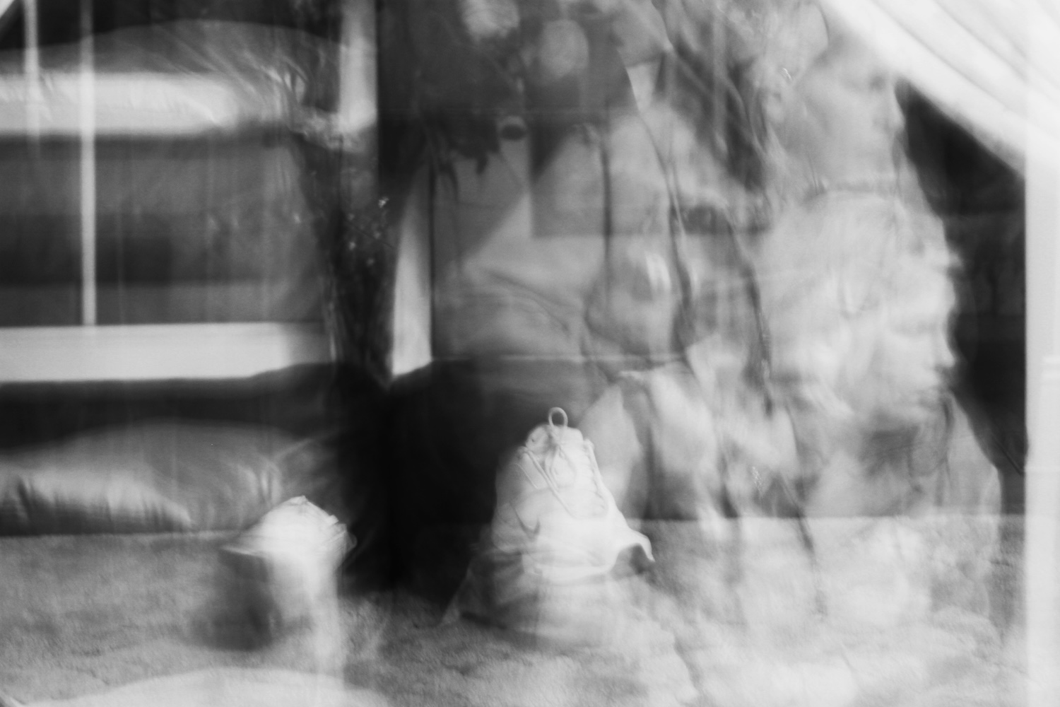 Rest, 2011, pigment on Hahnemühle Photo Rag, © Leanne McDonagh | Bafushia (a physically bound process of forward movement) | Wednesday 29 January  – Sunday 8 June 2025 | Hugh Lane Gallery | Image: Rest, 2011, pigment on Hahnemühle Photo Rag, © Leanne McDonagh | black-and-white photo which gradually reveals recognisable objects out of a superposition of blurred images – we see what seem to be the legs and runners of someone sitting, wearing black jeans, facing the camera?; a sash window?; a cartoon face with a mop of black hair; a double exposure of someone at the right of the image – a face looking to their left out of the image, what seems to be bedding of some sort; a silver spoon?;and just possibly the face of a chimp