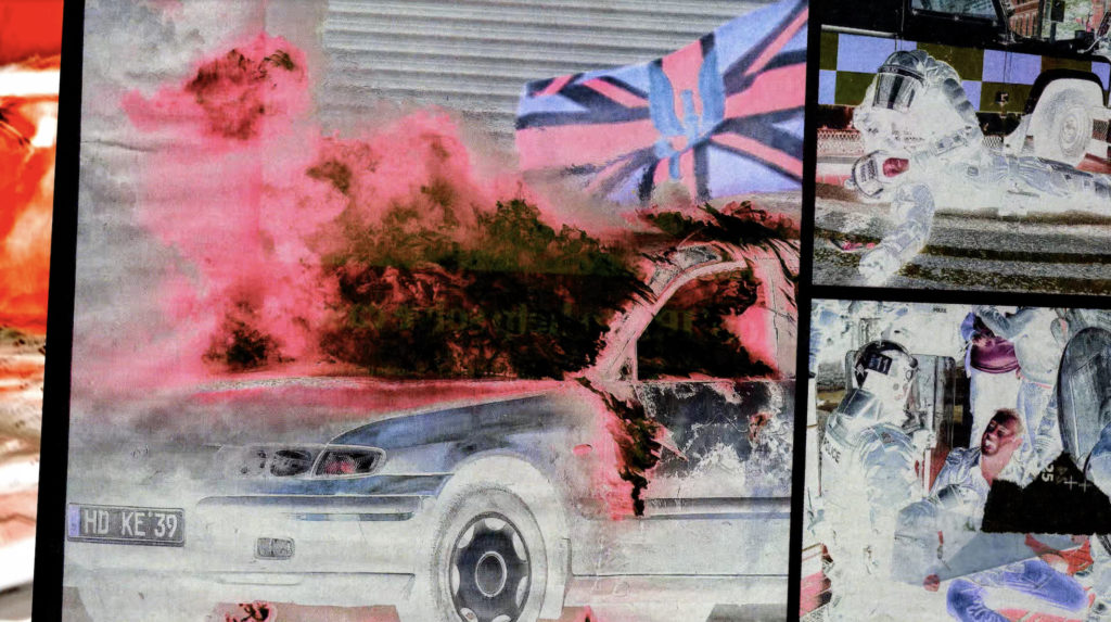 Eoghan Ryan, Circle A (2024). Film still courtesy of the Artist | Staying with the Trouble | Friday 2 May  – Sunday 21 September 2025 | IMMA | Image: Eoghan Ryan, Circle A (2024). Film still courtesy of the Artist | the still suggests four different frames; the main frame, taking up most of the image, is of what appears to be a burning car, its windscren smashed and flames or smoke coming out; it is hard to be very sure of what’s happening, as the colours are reversed / in negative; if the colours were not reversed, then the apparent union jack flying above the car would not be red, black and blue, but green, white and orange…; the flag has some sort of eagle-like logo in the middle; the smaller frame top right appears to be police officer attending to a fallen colleague – or they could be soldiers; again, the colours are reversed; the bottom frame is similar, though with odd patches superimposed; the leftmost frame is just a sliver of mostly orange, with bits of white  