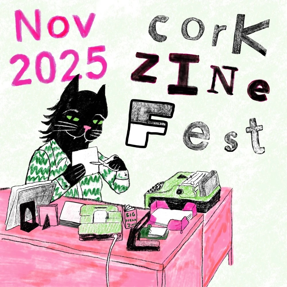 Cork Zine Fest | Wednesday 5 November  – Sunday 30 November 2025 | Triskel Arts Centre | Image: cartoonish drawing of a black cat apprently in the process of making a zine – it looks happy as it sits at a pink desk and cuts a piece of paper; we see a landline and a typewriter on the desk, and bits of actual paper; the cat is wearing a jacket that is white with squiggly green lines; its nose is pink, its eyes green; on the ‘wall’ behind the cat we read “Nov 2025” in pink, and “Cork Zine Fest” in black, white grey 