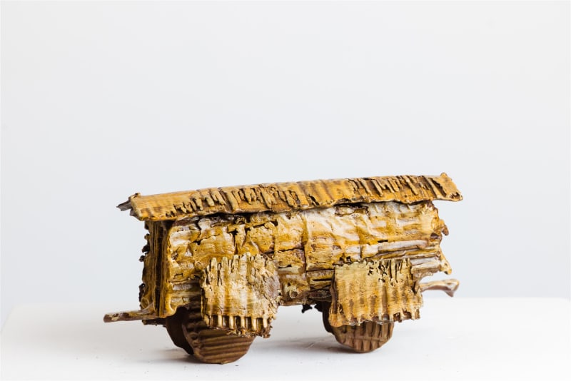 Tim Morris: Boxcar 8, bronze, unique 12 x 25 x 12cm | Tim Morris: Boxcars | Wednesday 8 January 2025  – Saturday 31 January 2026 | Solomon Fine Art | Image: Tim Morris: Boxcar 8, bronze, unique 12 x 25 x 12cm | photo of a bronze object – a boxcar viewed from the side, only the patterning of the surfaces if very much like you would see with cardboard, where parts of the surface have been torn away to reveal the rilling; the view is from the side; the wheels look almost like biscuits; the background is a photo-studio white with soft shadows 