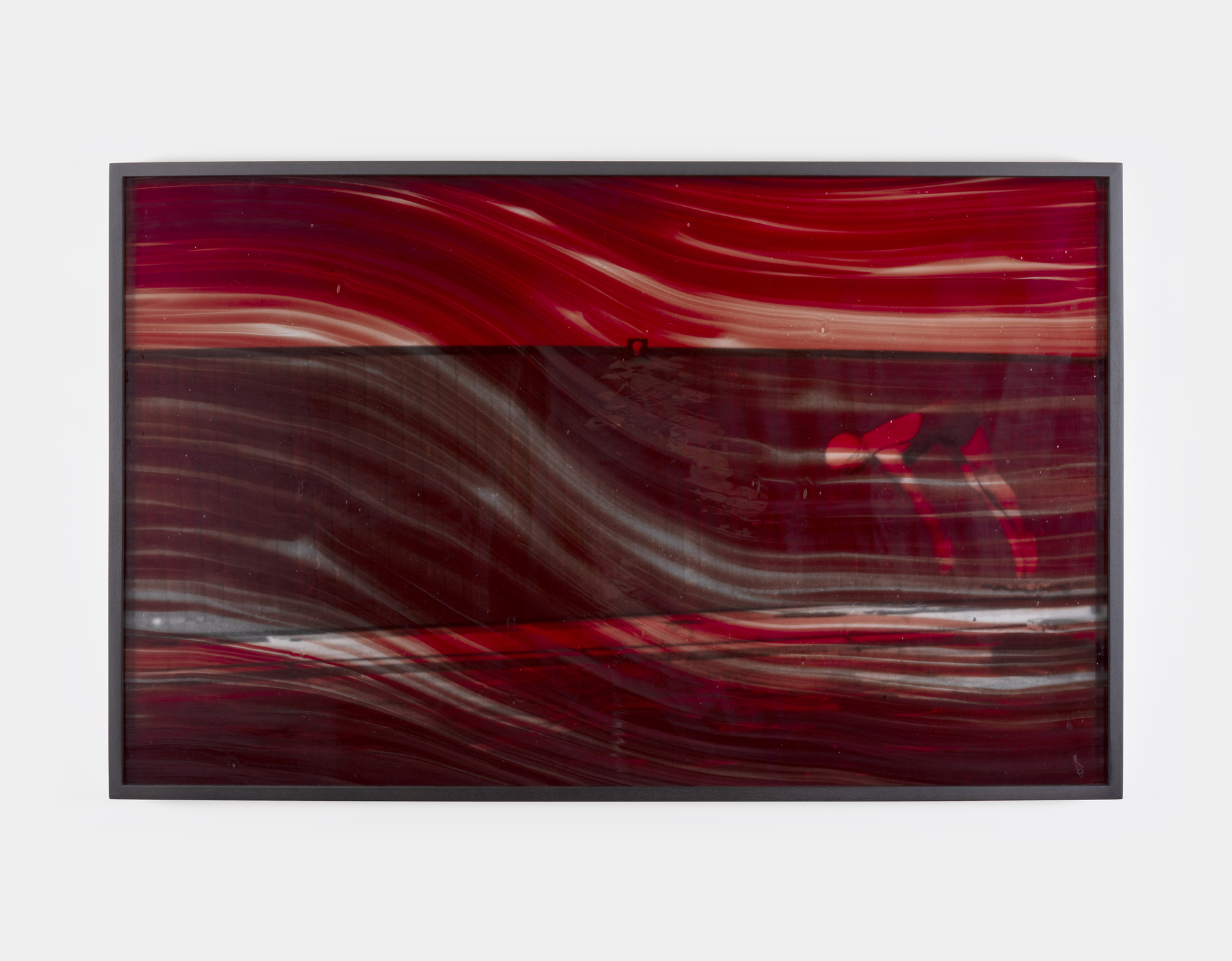 Dorothy Cross: Bloodlines Series (Jackknife dive), 2025 | Dorothy Cross: Bloodlines | Wednesday 21 January  – Saturday 14 February 2026 | Kerlin Gallery | Image: Dorothy Cross: Bloodlines Series (Jackknife dive), 2025 |  framed black-and-white photo showing someone in bathing suit and white cap diving into, probalby, the sea; we see what seems to be a wall nearer the camera, and possibly one in the distance; the figure is seen side-on, at the right side of the canvas; the figure is bent, doing the dive; the whole image is tinged red by what is like a translucent huge brushstroke of blood  