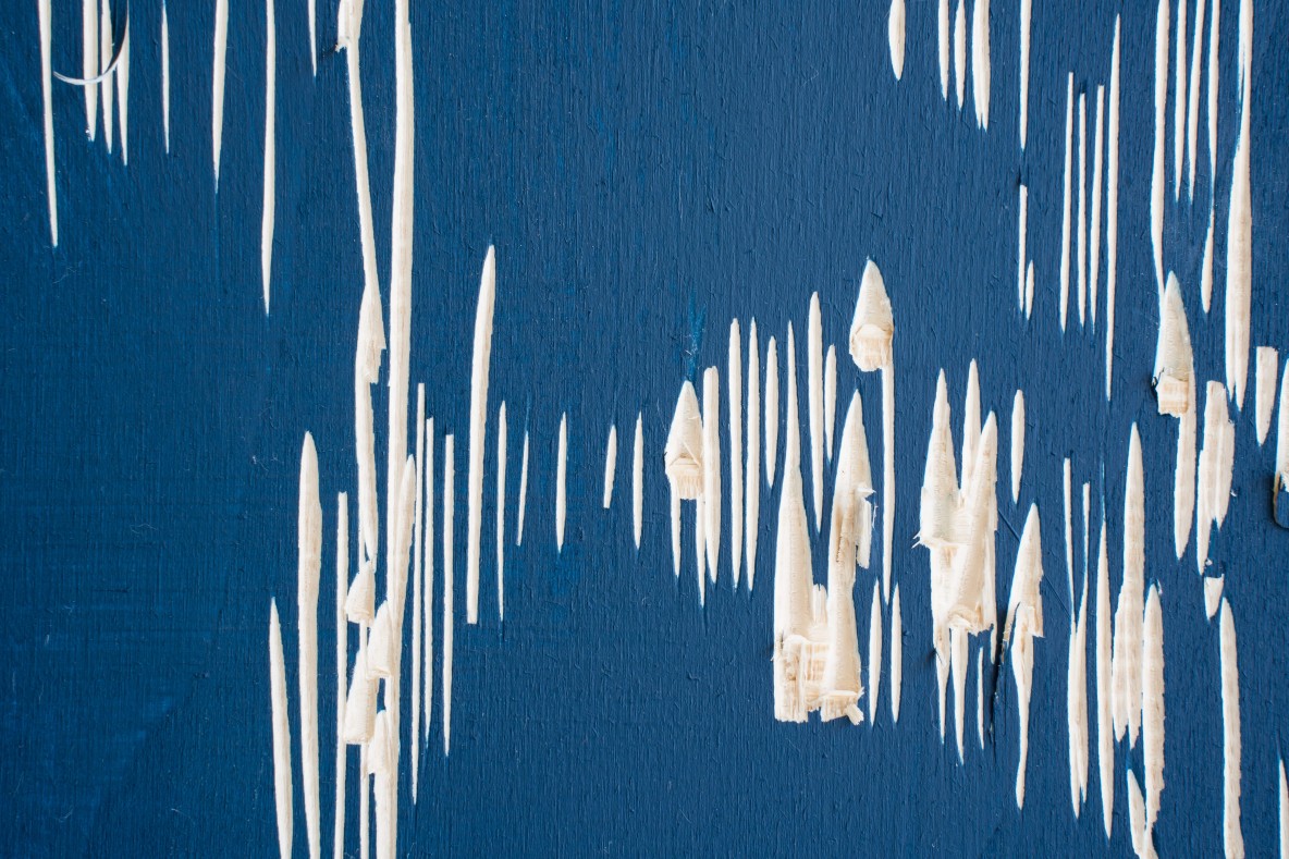 Oisín Tozer: A Fragile Line | Thursday 26 February  – Saturday 11 April 2026 | The LAB | Image: photo; a navy-ish blue surface with vertical cuts in it, revealing a cream-white subsurface; the cuts look as though they were made by a lino- or wood-cutting tool; almost all are vertical, some shorter some longer, thicker, etc. 