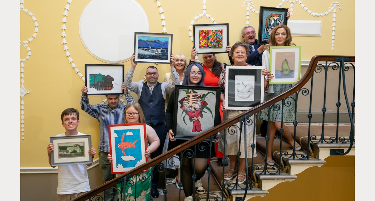 CAC group (1) | CA Collective at the RHA | Friday 20 March  – Sunday 19 April 2026 | Royal Hibernian Academy | CA25 Collective Artists | photo of 10 people standing on stairs in a fairly ornate building, judging by the wall behind them. Each person is hold a framed artwork as they look towards the camera and smile 