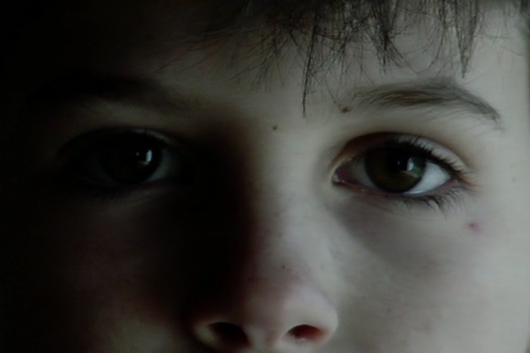 Simon Reilly: Mind's Eye, 2006, hi-definition video transfer to DVD, 2-channel audio; duration: 6 min 30 sec | Simon Reilly: Mind’s Eye | Saturday 21 February  – Friday 22 May 2026 | Butler Gallery | Simon Reilly: Mind's Eye, 2006, hi-definition video transfer to DVD, 2-channel audio; duration: 6 min 30 sec. Butler Gallery Permanent Collection, donated by Betty Cunningham (NYC) | close-up still image of the face of a child, cropped to just show eyes, eyebrows, nose; the left side of the face, as we see it, is almost in darkness, while the other side is lit from the right 