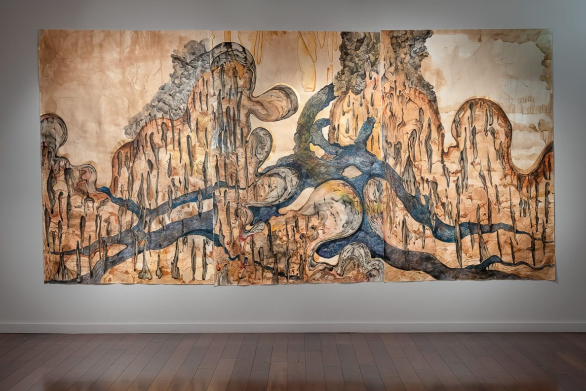 Hina Khan, No Borders, 2022. Coffee wash, gouache, watercolour, Indian ink, and marker on paper; 200 x 450 cm. Photograph: the artist. Courtesy of the artist | Hina Khan: Red Storm | Saturday 16 May  – Wednesday 27 May 2026 | SIRIUS | Hina Khan, No Borders, 2022. Coffee wash, gouache, watercolour, Indian ink, and marker on paper; 200 x 450 cm. Photograph: the artist. Courtesy of the artist | map-like piece, though the shapes are also organic, like a snaking greyish-blue shape that resembles above-ground tree roots; in other ways it looks like coastline and a river; but there is a texture of vertical marks / shapes that somewhat resemble the colour and surface of cork (the tree) 